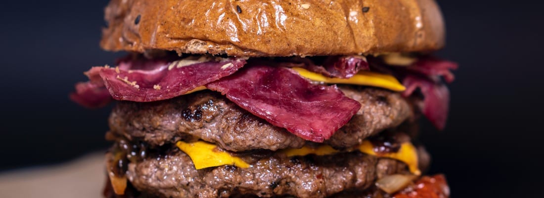 Dubbele burger met bacon en gesmolten cheddar tussen een glanzend broodje