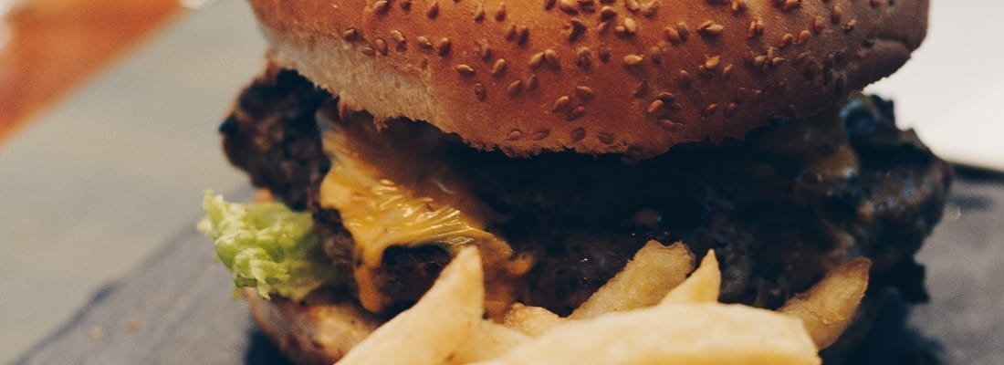 Huisburger met sesambroodje, cheddar en verse frieten ernaast