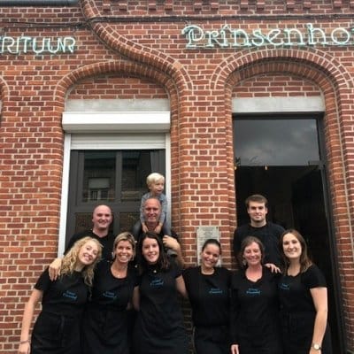 De ploeg van Frituur Prinsenhof voor de bakstenen gevel, met een kind op de schouders