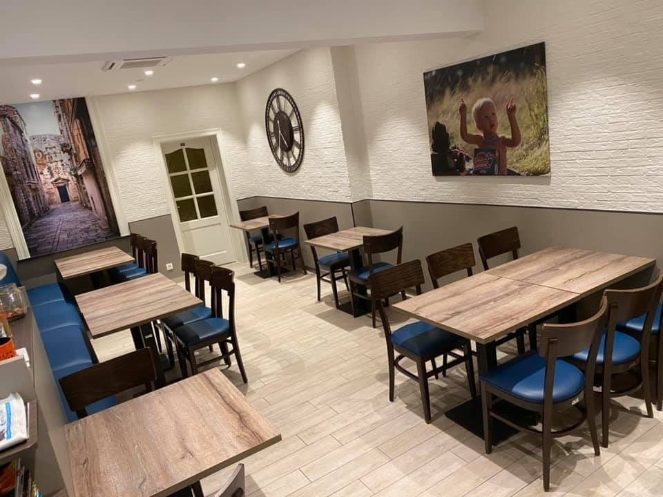 De eetzaal van Frituur Prinsenhof met houten tafels, blauwe stoelkussens en witte baksteenmuren