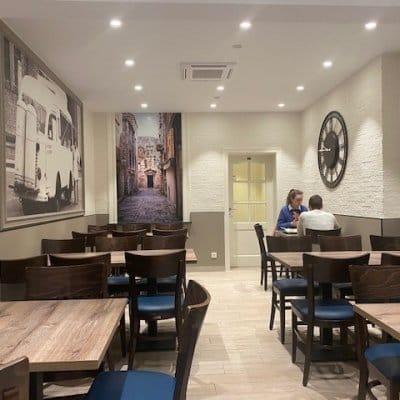 Gasten aan tafel in de zithoek van Frituur Prinsenhof, met grote fotoprints aan de muur