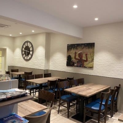 Zithoek met houten tafels, de wandklok en een grote fotoprint aan de muur