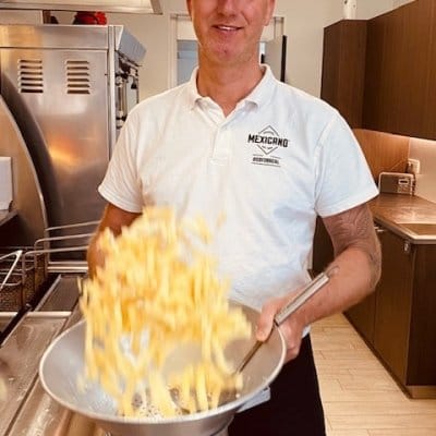 Jurgen schept vers gebakken frieten uit de frituurmand in de keuken van Frituur Prinsenhof