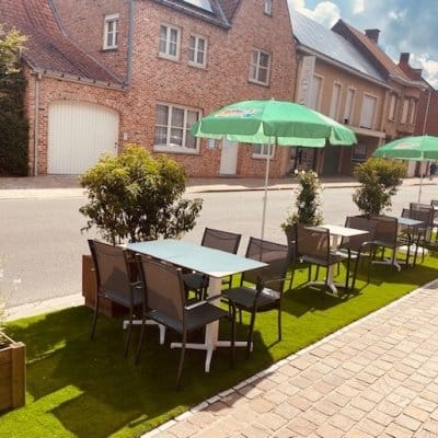 Het terras van Frituur Prinsenhof met groene parasols en tafels op kunstgras